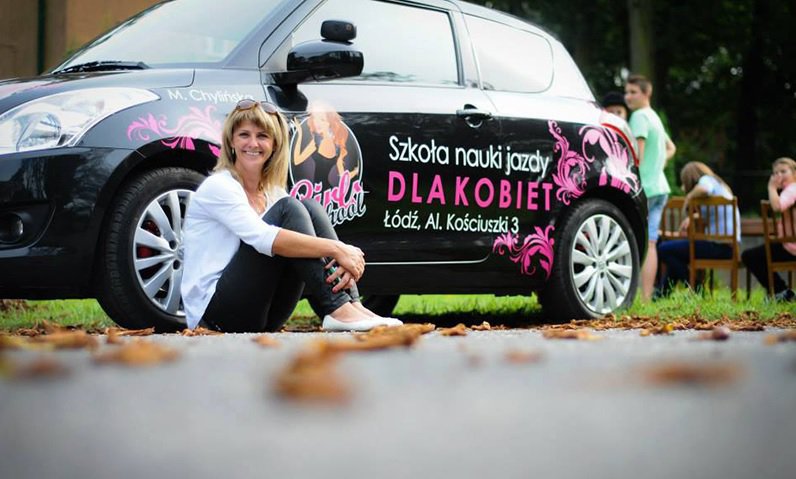 kobieta siedząca przy samochodzie szkoleniowym " Szkoła nauki jazdy dla kobiet "