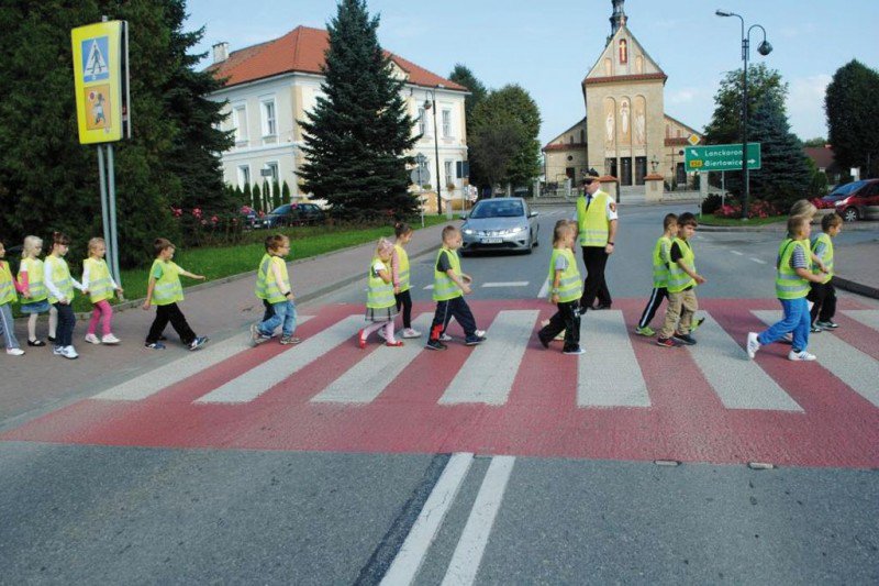 dzieci przechodzące przez jezdnię w kamizelkach odblaskowych