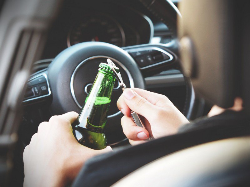 mężczyzna otwierający alkohol w samochodzie