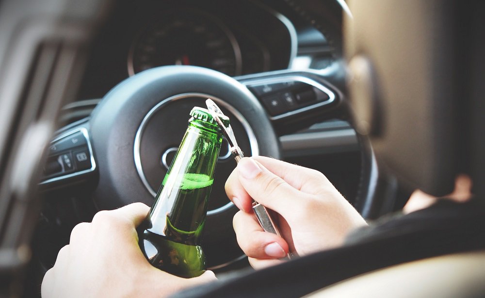 mężczyzna otwierający alkohol w samochodzie