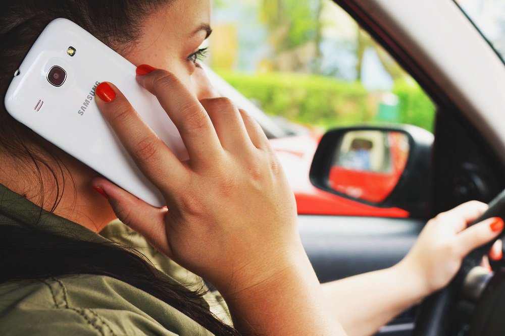 kobieta rozmawiająca przez telefon w trakcie jazdy samochodem